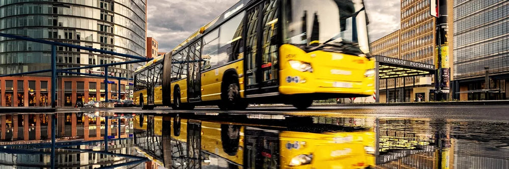 Gelber BVG-Gelenkbus am Potsdamer Platz mit Spiegelung in Pfütze
