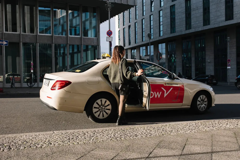Frau steigt in FREENOW-Taxi in der Großstadt ein